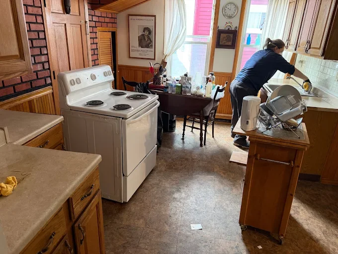 Pest control technician treating kitchen with wood cabinets and vintage stove