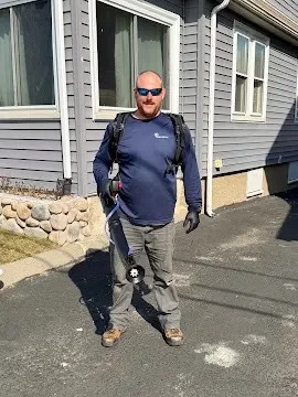 Pest control technician treating exterior foundation and perimeter of residential home